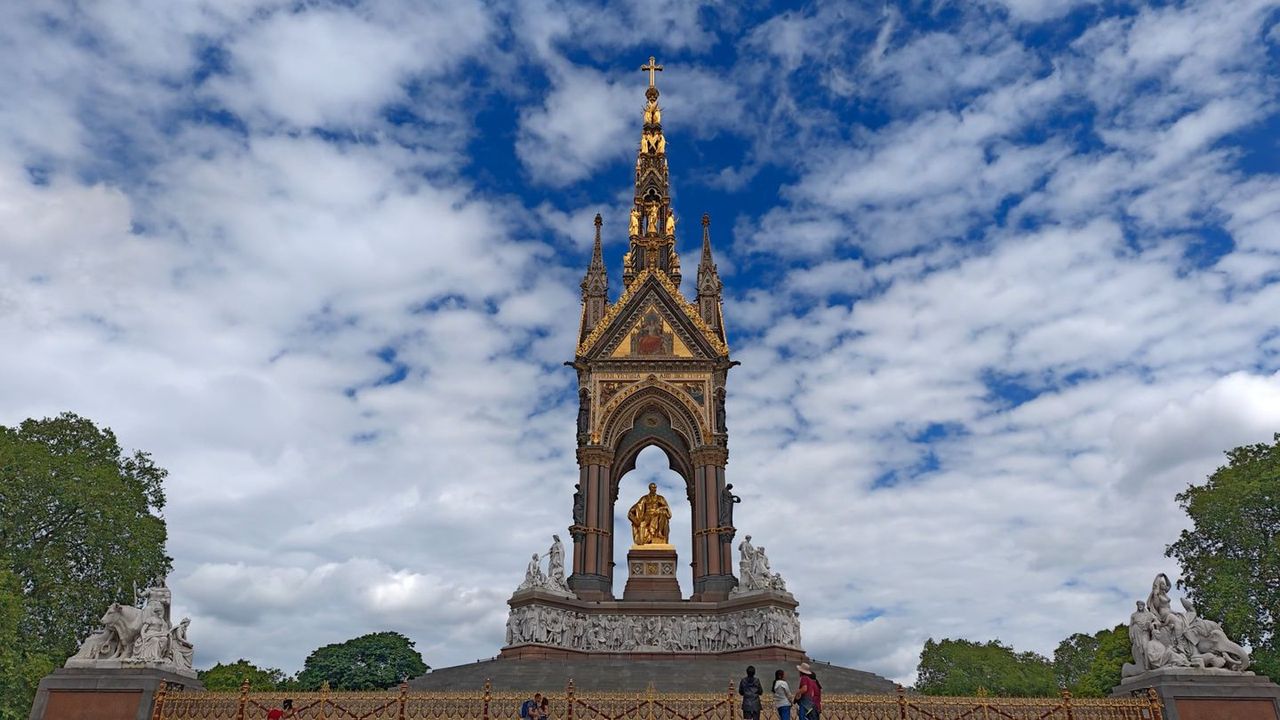 The Albert Memorial, a tall gilded and spired monument, under a blue sky with clouds