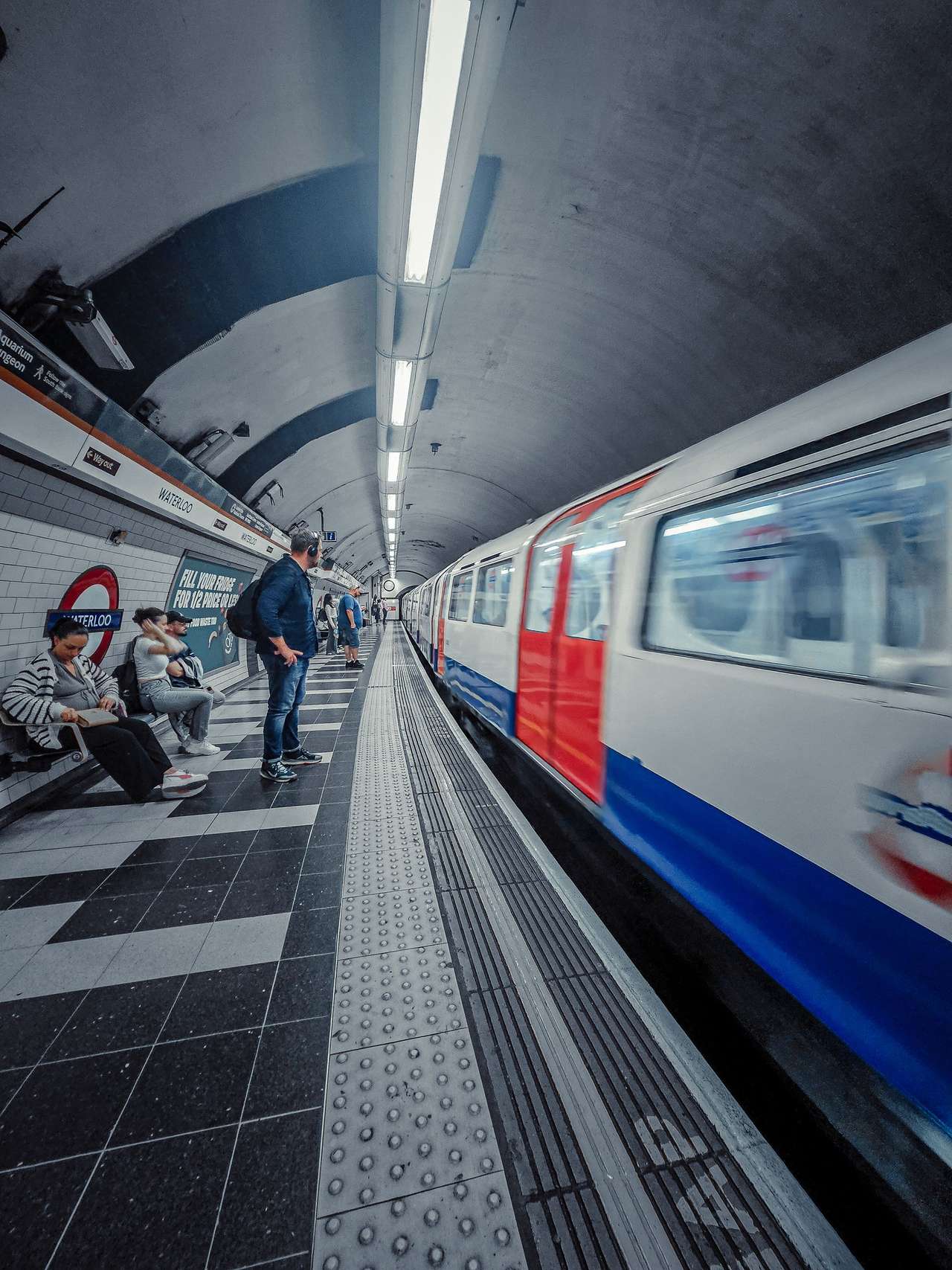 A red, white and blue Tube train pulling into a platform, seen from low down
