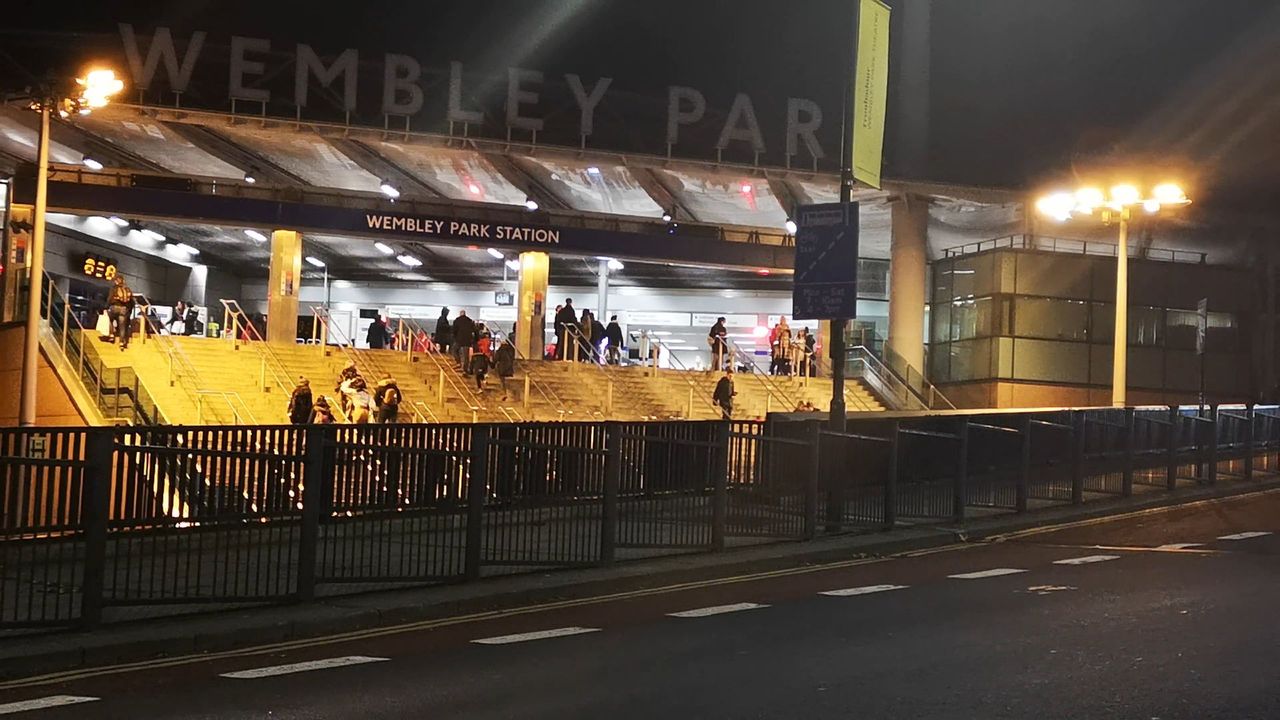 The wide steps and canopy of Wembley Park station at night, with WEMBLEY PARK in large letters on the roof